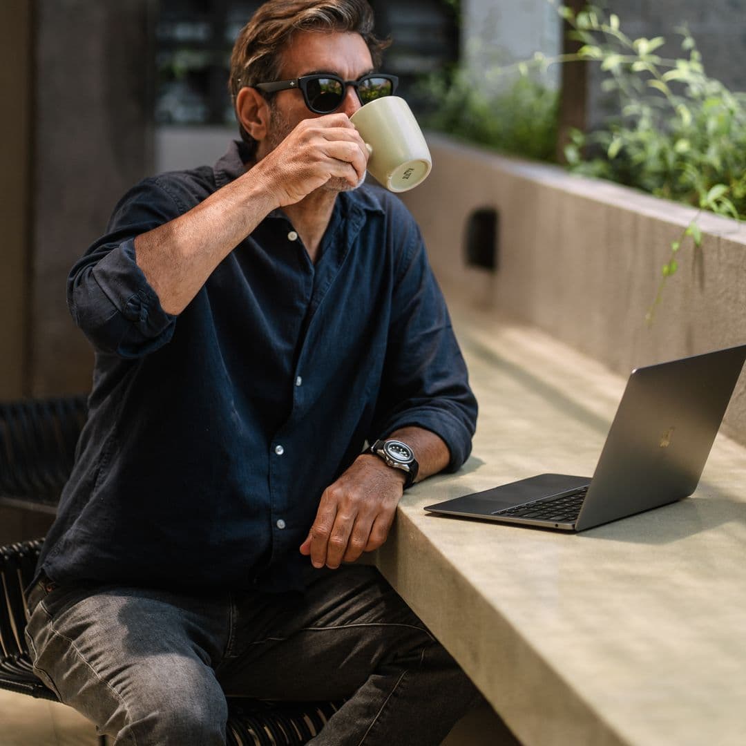 Guest sipping coffee over his laptop at a planted concrete work ledge at TheHub