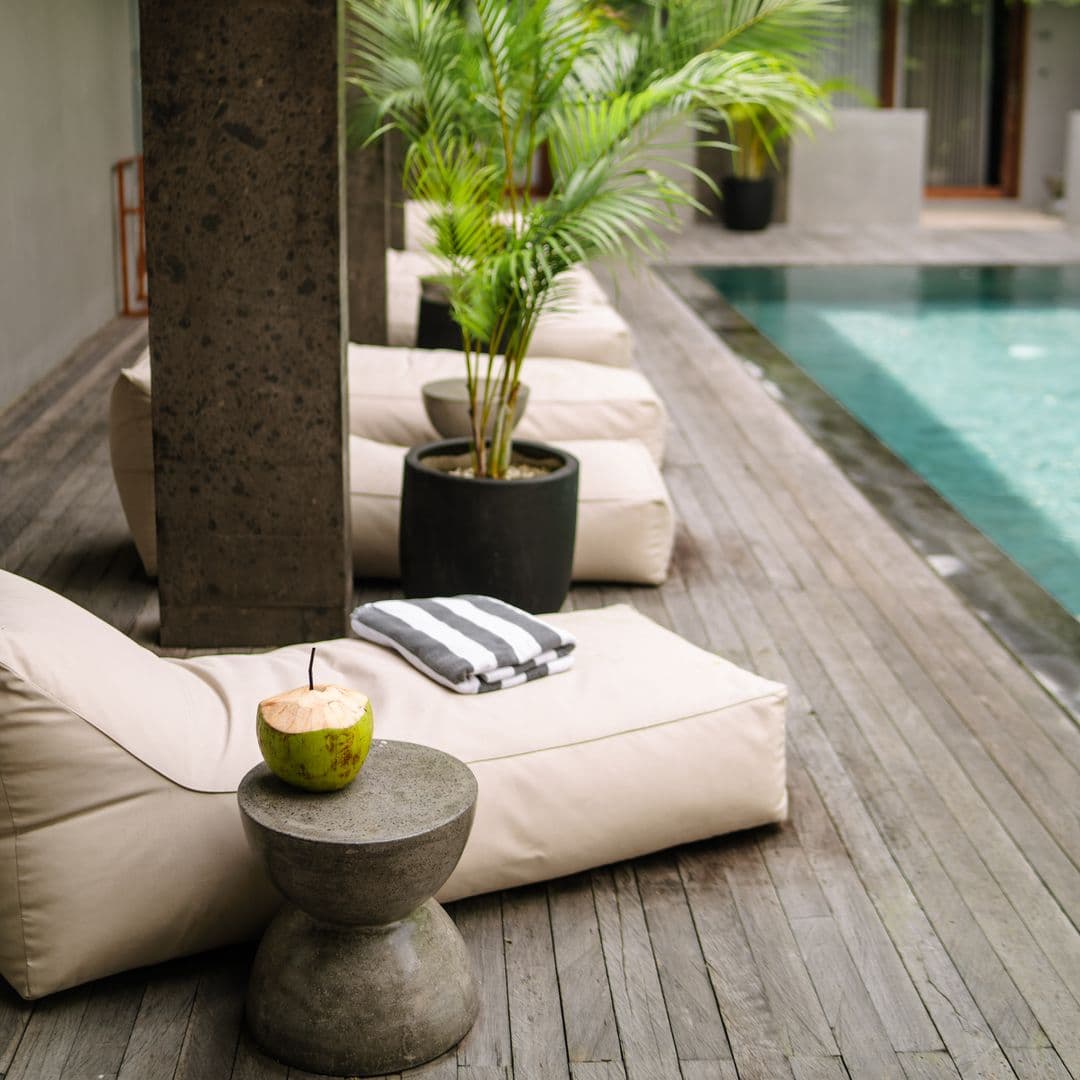 Fresh coconut on a stone side table beside pool loungers on TheHub's teak pool deck