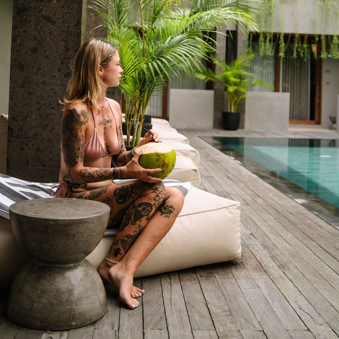 Guest enjoying a coconut at the pool edge beneath TheHub's plant-draped facade