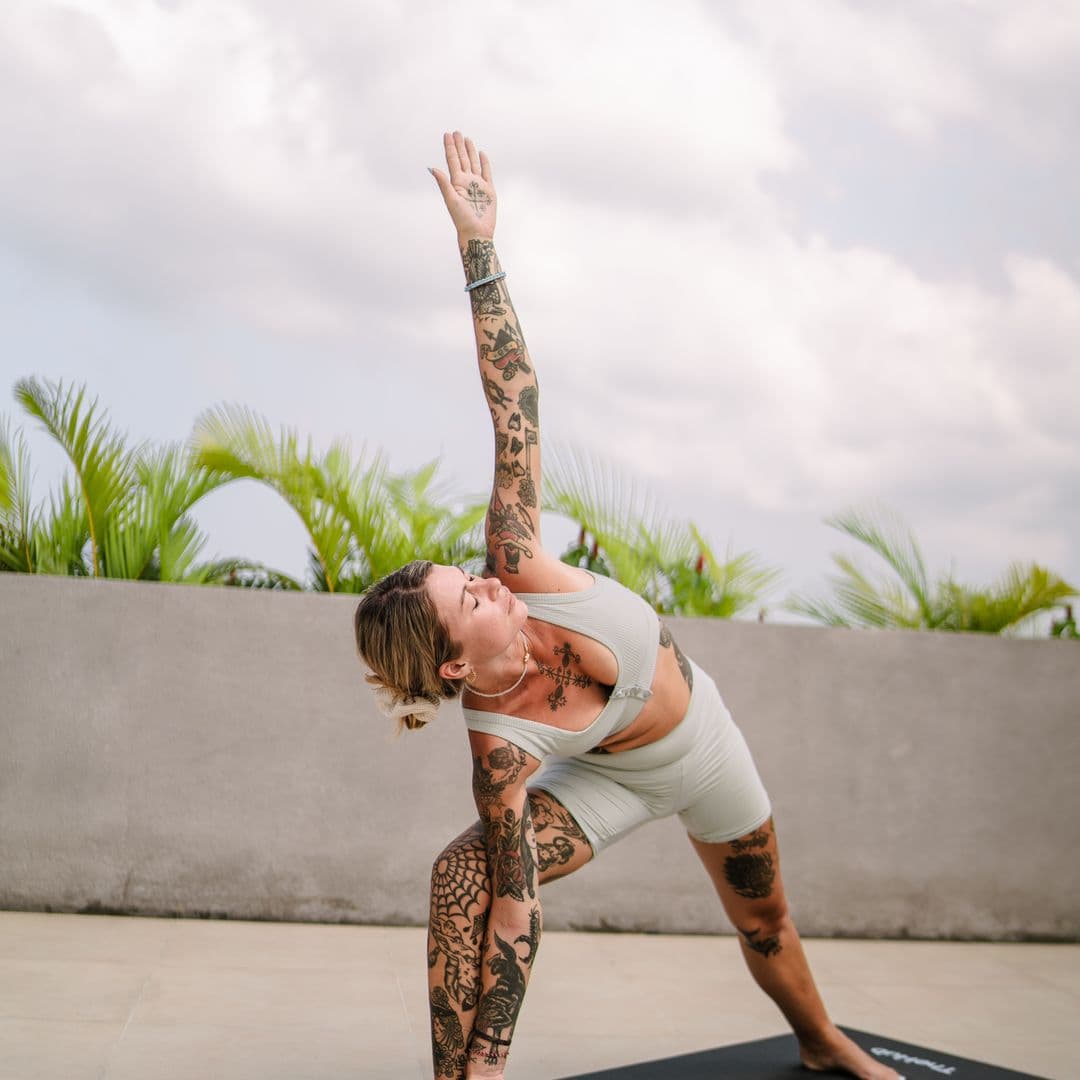 Guest in a standing yoga pose on TheHub's rooftop deck under an open sky