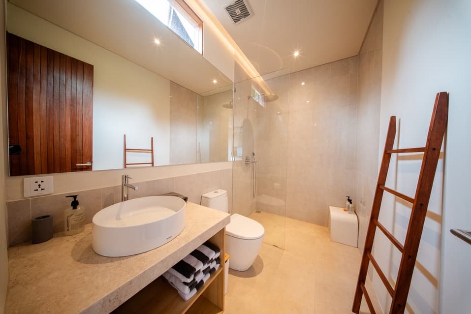 Ensuite bathroom with a freestanding oval basin, walk-in rain shower and warm timber ladder shelf